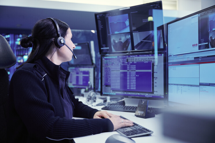 Securitas professional sitting at their desk and looking at multiple screens for remote guarding.