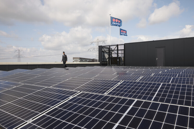 Beveiliger loopt controleronde over dak vol zonnepanelen
