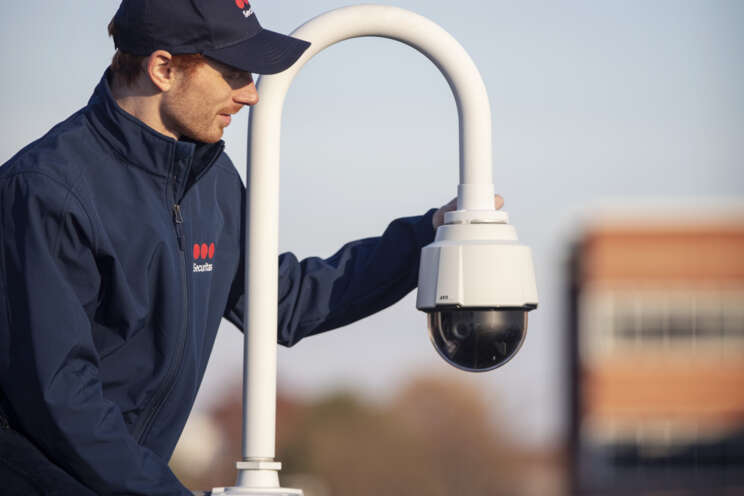 Securitas employee on top of a building installing video surveillance camera